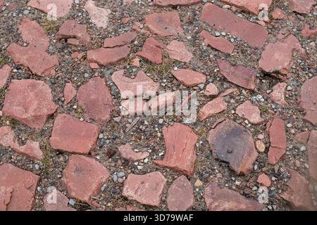 Old red cobblestones, ancient pavement with uneven brown stones. Ancient brick cobblestone pavement with large stones. Stock Photo