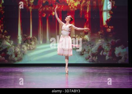 Ballet dancer en pointe in arabesque on theater stage with colonnade Stock Photo