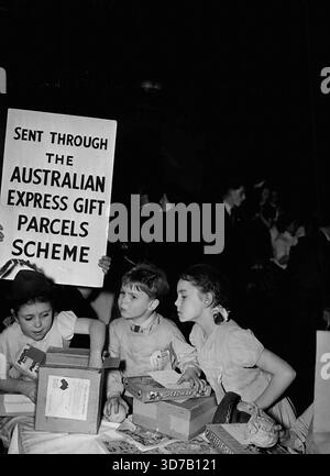 Gala Day For St Pancras Children -- Anne Bowyer (7), un-packing a food parcel from Australia at a distribution of food parcels at the annual Fitzroy Tavern (London) children's party held in St. Pancras Town Hall (London). The fond parcels were sent from Hoyts Theatre Ltd. (Sydney) through the Express Gift Parcels Scheme and were part of the Christmas gift of 100,000 parcel to mark posting of the two millionth gift parcel. This party is given yearly through contributions from patrons of the Fitzroy Tavern. During the year £328 was accumulated on the ceiling of the tavern. January 08, 1950. Stock Photo