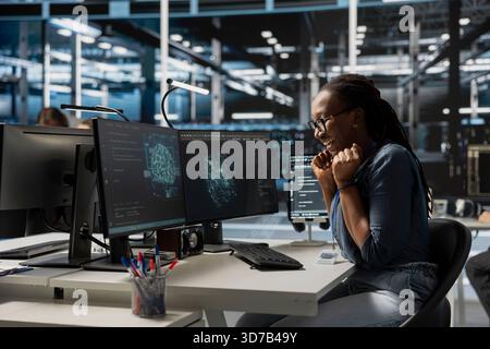 Excited engineer in data center celebrating successful AI implementation. Smiling server hub employee excited after artificial intelligence model completes training process with optimal results Stock Photo