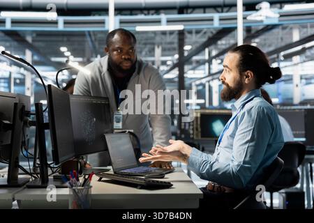Team of computer scientists using PC in server farm, analyzing data. Team working data center office staff members examining infrastructure, ensuring system integrity and security Stock Photo