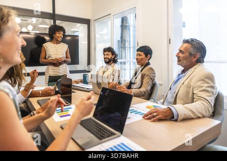 Multiracial team of business colleagues actively collaborating and discussing project strategies while attending a professional meeting in a modern of Stock Photo