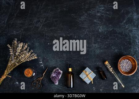 Rustic arrangement of lavender, crystals and natural spa accessories on dark textured background. Top view, flat lay, copy space. Stock Photo