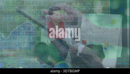 Presenting woman in red top gesturing with laptop toward flipchart, financial data overlaying room Stock Photo