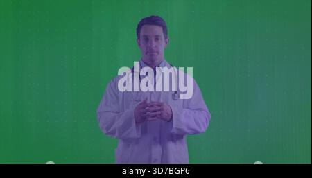 Standing doctor wearing white lab coat, collared shirt, necktie, stethoscope in green chroma studio Stock Photo