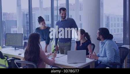 Reviewing plans, team wearing business-casual leaning over meeting table, laptop and safety vests Stock Photo
