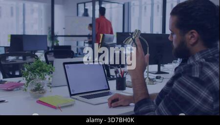 Reaching bearded man in dark-plaid shirt fixing brass lamp at office with blank laptop, copy space Stock Photo