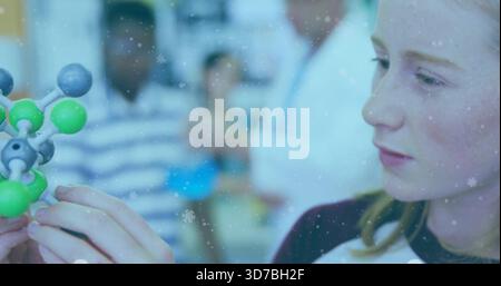 Studying teen wearing dark collar holding molecular model in lab with teacher lab coat, copy space Stock Photo