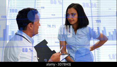 Talking doctor and nurse in blue scrubs reviewing blue overlays in clinic, holding black clipboard Stock Photo
