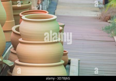 Stacked unglazed terracotta clay pots displayed outdoors next to a wooden deck ready for gardening and landscape design Stock Photo