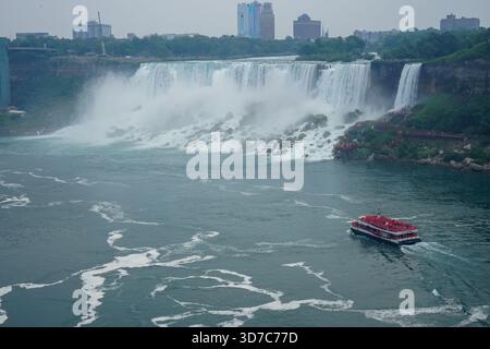 The Canadian Niagara City Cruises boat sails past American Falls on an overcast, rainy day on the Niagara River in Niagara Falls, Ontario, Canada Stock Photo