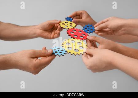 Many hands with colorful gears on light background Stock Photo