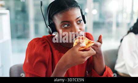 Lunch break, pizza and woman with headset in contact center, customer service and eating fast food. Hungry, work pause and virtual assistant with Stock Photo