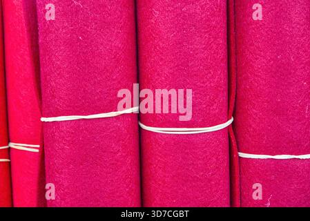 Vibrant felt fabric rolls in a textile market displaying bright fuchsia and pink shades, ready for craft and design projects Stock Photo