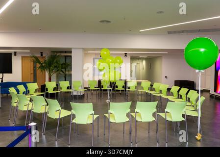 A modern conference room set up with vibrant green chairs arranged in a circle. the room features large green balloons adding a festive touch, perfect Stock Photo