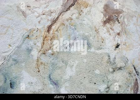 Decayed wall surface with cracks, stains, and weathered textures creating an abstract pattern Stock Photo