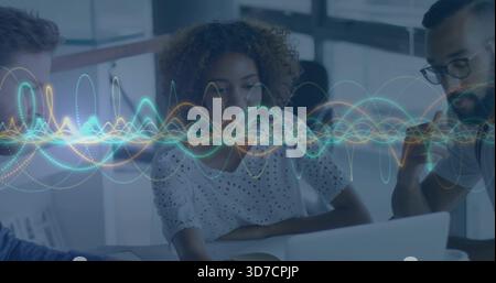 Reviewing three-person team leaning over laptop in office, woman in white eyelet blouse, waveform Stock Photo