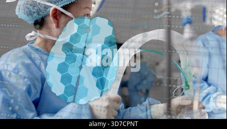 Operating surgeon in blue gown holding C-arm in OR with anesthesia mask, brain-overlay, copy space Stock Photo