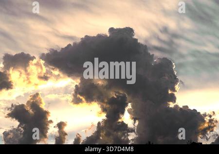Clouds gather across dramatic sky. Dark stormy cumulus shapes contrast bright sunlight, creating ominous thundercloud formations in powerful summer we Stock Photo