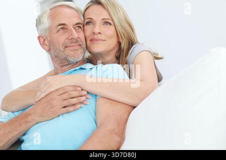 Relax, couple and thinking with hug in home for daydreaming, bonding together and connection. Love, mature people and reflection with embrace in house Stock Photo