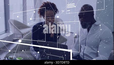 Analyzing two colleagues in business attire studying monitor at office desk, with digital overlay Stock Photo