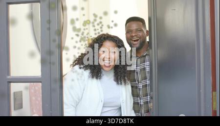 Smiling woman and man standing in home entryway, wearing sweater and plaid shirt, showing sidelight Stock Photo