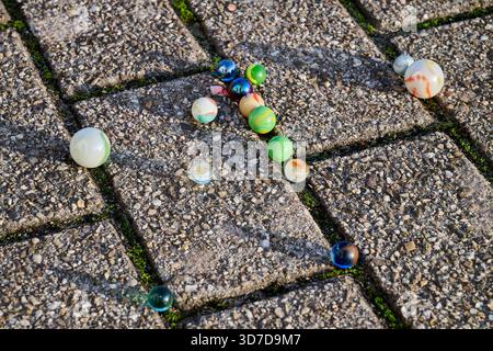Colored marbles on a paved floor Stock Photo