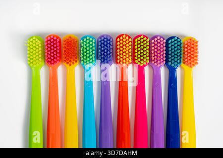 Multicolored toothbrushes lie in a row on a white isolated background Stock Photo