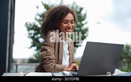 coder working outside, software engineer diligently coding outside near glass skyscraper with coffee Stock Photo