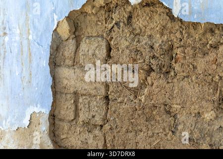 Close-up of a weathered adobe wall with peeling plaster, revealing mud bricks and natural textures, suitable for backgrounds and construction themes. Stock Photo