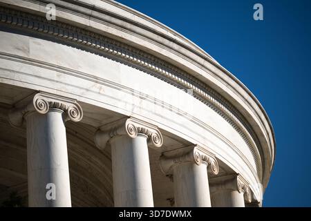 WASHINGTON DC — The Ionic columns and neoclassical architectural details of the Jefferson Memorial are prominently featured. This monument is dedicated to Thomas Jefferson, the third U.S. President, and is a prime example of Neoclassical architecture. Designed by John Russell Pope, its circular domed structure is inspired by the Pantheon in Rome. The memorial is constructed from white Imperial Danby marble from Vermont. Dedicated in 1943, it is situated on the Tidal Basin, a prominent landmark in the nation's capital. Stock Photo