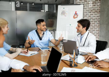 Cheerful multiracial doctors having conversation, using gadgets Stock Photo
