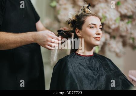 Woman in a hair salon chair getting styled with extensions by a professional stylist Stock Photo