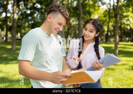 Students Collaborating Outdoors While Reviewing Notes in a Park on a Sunny Day Stock Photo