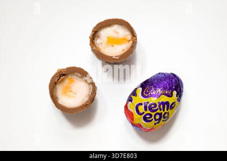 Cadbury Creme eggs on white background with one cut in half showing the gooey fondant inside Stock Photo