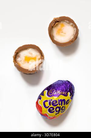 Cadbury Creme eggs on white background with one cut in half showing the gooey fondant inside Stock Photo