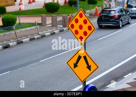 Arrow sign and red dots on yellow background on city road. Stock Photo