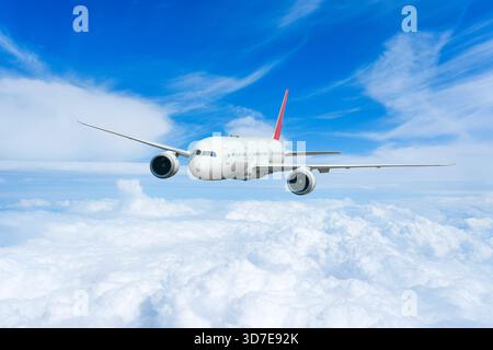 Airplane in the flight, travel background with airplane flying in the blue sky over the cloudscape. Flying airplane with blank livery. Stock Photo