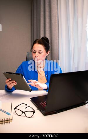 Student attending virtual university class via video conference. Young woman actively participates in online lecture, taking notes on laptop. Distance Stock Photo