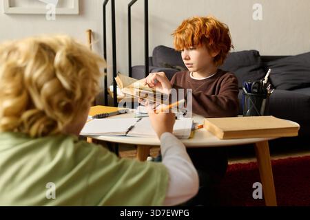 Two boys enjoy a reading session at home, sharing stories and laughter in comfort. Stock Photo