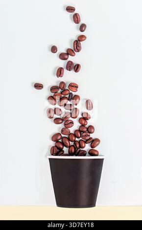 Coffee beans falling in to a paper cup Stock Photo