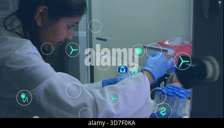 Leaning lab-tech handling blue tubes at lab bench, lab-coat, blue gloves, holo icons, copy space Stock Photo