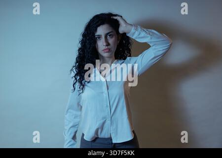 Young woman posing, expressing stress, worry, or deep thought with hand on head Stock Photo