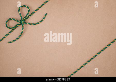 Green and Gold Christmas String Tied in Bow on Kraft Paper Background Stock Photo