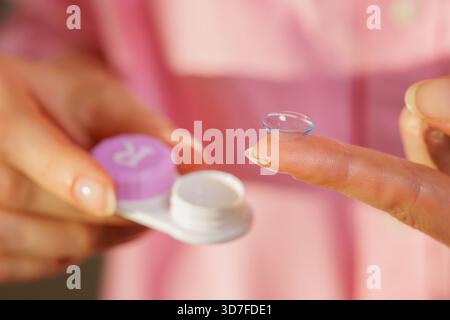 Close up of soft contact lens on finger with open case in female hands, concept of daily hygienic eye vision correction at home Stock Photo