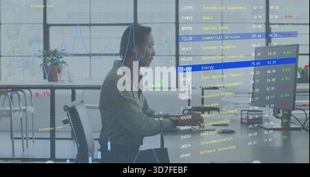 Working mid adult man in light shirt using desktop computer at open office, with financial overlays Stock Photo