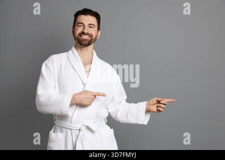 Man in bathrobe pointing at something on grey background Stock Photo