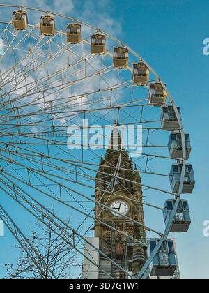 Manchester town hall tower clock behind the big wheel in Albert Square which is part of the Manchester Christmas Markets Stock Photo