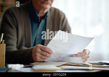 Senior Man Examining Financial Documents and Calculating Expenses Stock Photo