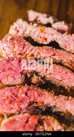Beautiful ribeye steaks on a wooden board, perfectly seared with a golden crust and rare interior. Ready to slice and serve. Ideal for gourmet dining Stock Photo